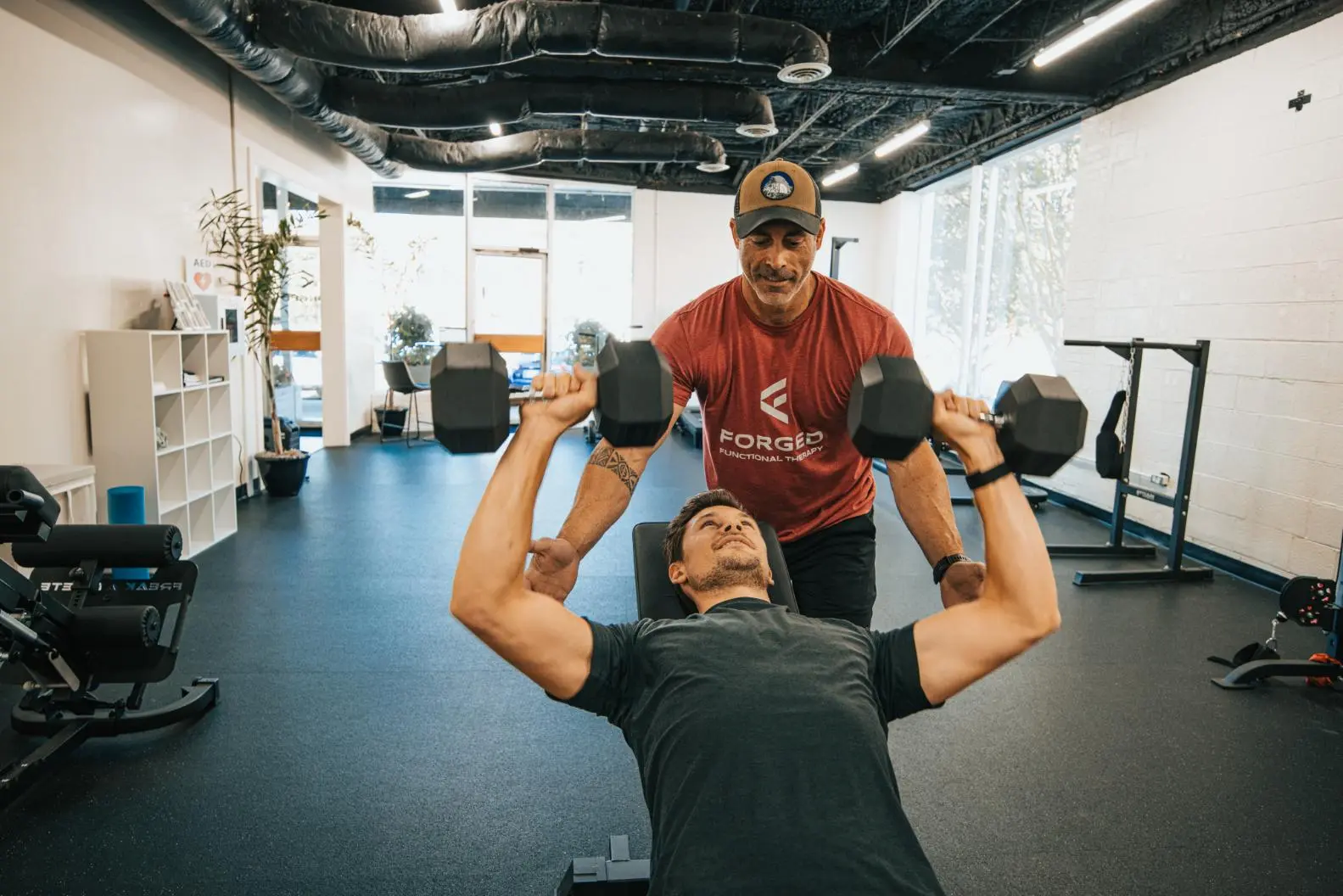 Corey Church, personal trainer at Forged Functional Therapy, helping a client with strength training.